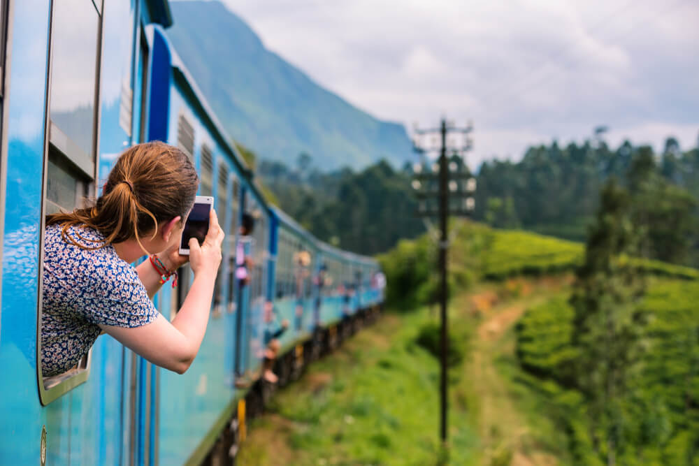 鉄道と山の風景の写真を撮る女性