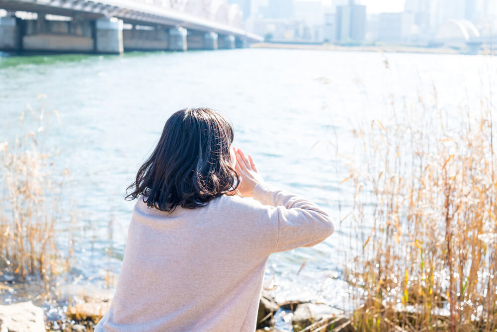大きい川に向かって叫ぶ女性